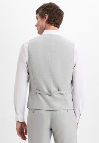Light gray tailored vest with a textured weave, adjustable back strap, and worn over a white dress shirt with cufflinks.