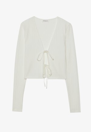 Hvit ribbet crop top med lange ermer, dyp V-hals og snorbinding foran. Myk tekstur med subtil mønstring.