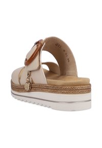 Beige Sandale mit glatter Oberfläche, breitem Riemen, runder Plastikverzierung und strukturiertem Sohlenprofil. Verfügt über einen goldenen Anhänger und eine erhöhte Plattform.