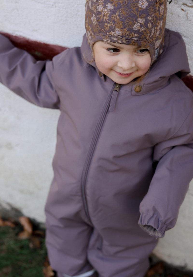 Purple insulated snowsuit with a zip closure and elastic cuffs, paired with a floral-patterned brown hat, suitable for cold weather.