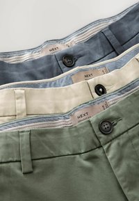 Trei perechi de pantaloni drepti pentru bărbați, în gri închis, bej și verde măsliniu. Fiecare are o închidere cu buton și o căptușeală cu un model contrastant.