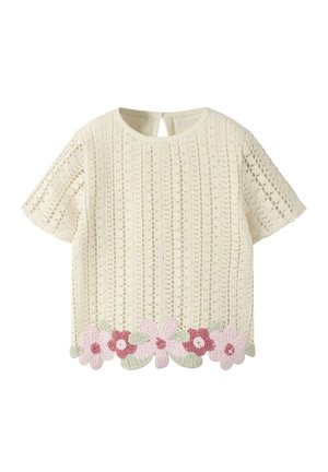 Cremefarvet strikket top med korte ærmer, med lodret hulmønster og lyserøde og røde hæklede blomster med grønne blade langs kanten.