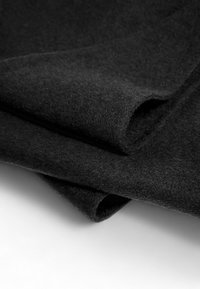 Black felt textile with a soft texture, featuring dark, smooth fibers, folded to show a slight curve and layered depth.