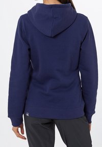 Granatowa bluza z kapturem o miękkiej fakturze, z prążkowanymi mankietami i dołem oraz metką z logo w lewym dolnym rogu. Prosty, casualowy design.