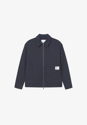 Marineblaue Jacke mit einem Reißverschluss vorne, aufgesetzten Taschen und einem kleinen Etikett auf der linken Tasche, mit strukturiertem Kragen und glattem Stoff.