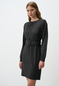 Robe en tricot gris avec des manches longues, un col rond et une taille ceinturée. Texture douce, longueur genou avec une coupe décontractée.
