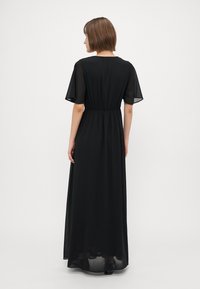 Black maxi dress featuring short, sheer sleeves, a fitted waist, and a flowing skirt. The fabric is lightweight and slightly translucent.