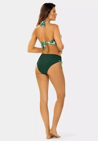 Zielony zestaw bikini z topem na szyję z tropikalnym wzorem, związanym z tyłu, oraz dopasowanymi wysokimi majtkami z wiązaniami po bokach.