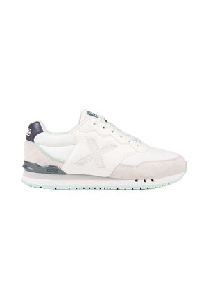 Zapatilla blanca y gris claro de corte bajo con cordones delanteros, logo texturizado "X" lateral y detalle negro en el talón sobre suela blanca.