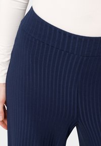 Pantalones de marino acanalados con una amplia cinturilla elástica. La tela es suave y texturizada, con rayas verticales que aportan un aspecto elegante.