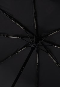 Black umbrella viewed from underneath, featuring a sturdy black pole, metallic ribs, and a smooth texture on the canopy fabric.