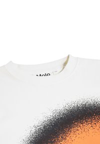 Camiseta de algodón blanca con cuello redondo y un diseño degradado que presenta puntos negros que se transforman en un vibrante naranja en la parte inferior.