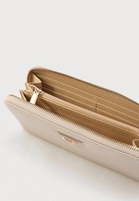 Beige portemonnee van textuurmateriaal, met een ritssluiting, meerdere kaartsleuven en een binnenvak met rits voor munten.