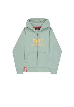 Mintgrüner Hoodie mit Reißverschluss, Fronttaschen, Kapuze mit Kordelzug, gelbes "Alpha Industries"-Logo und rotes Etikett am Saum.