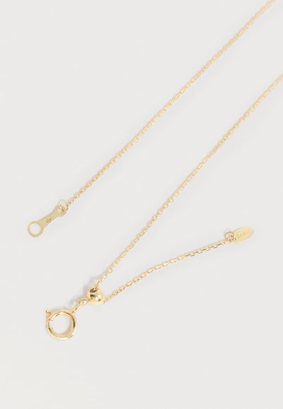 Λεπτό χρυσό κολιέ με αλυσίδα, στρογγυλό ελατήριο-κλείστρο και μικρή οβάλ ταυτότητα με χαραγμένη την επιγραφή "ΠΑΡΙΣΙ" σε ανοιχτό φόντο.