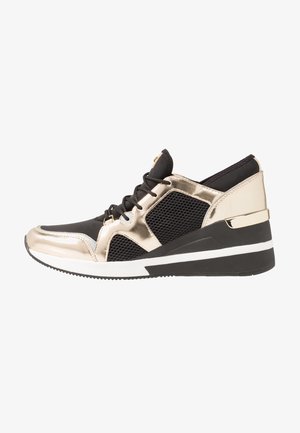 Czarny i metalicznie złoty sneaker z panelami z siateczki, sznurowaniem i koturnem. Posiada gumową podeszwę z białymi akcentami.