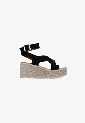 Sandalia de cuña de ante negro con correa en el tobillo y hebilla plateada, con suela plataforma de cuerda trenzada beige.