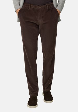 Braune Cordhosen mit glatter Textur, geradem Schnitt und seitlichen Taschen, kombiniert mit dunklen Schuhen und einem hellgrauen Pullover.