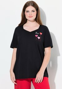 Zwart T-shirt met korte mouwen en V-hals met de tekst "Be mine" en roze ballonafbeeldingen aan de linkerkant. Zachte stof, losse pasvorm.