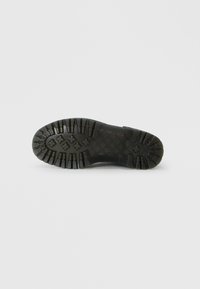 Talpa de pantof din cauciuc negru, cu crampoane adânci și un model de prindere. Design plat cu margini ridicate și un finisaj texturat pentru aderență.