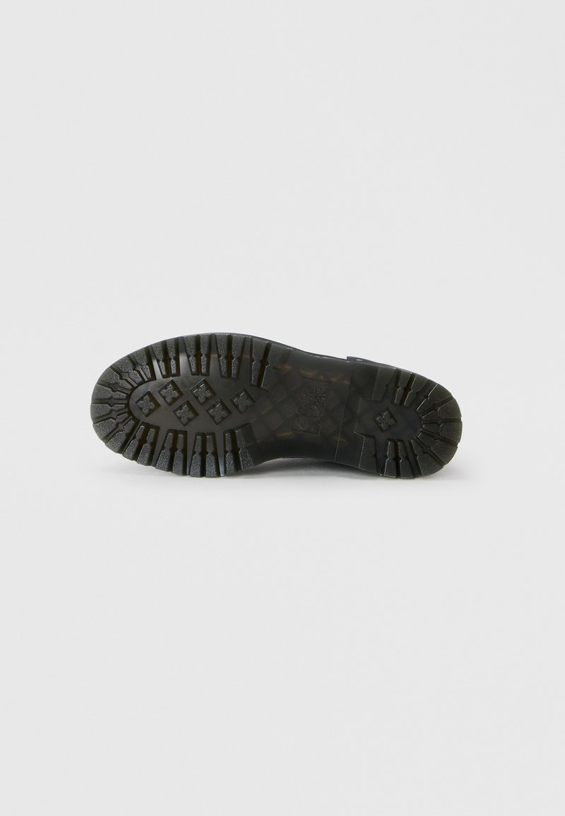 Semelle de chaussure en caoutchouc noir avec des rainures profondes et une surface antidérapante. Design plat avec des bords surélevés et une finition texturée pour une meilleure adhérence.