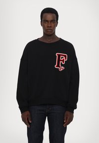 Zwart sweatshirt met een ruime pasvorm, ribgebreide manchetten, voorzien van een rood geborduurd "F"-logo op de borst en een zachte, gestructureerde stof.