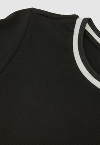 Czarny prążkowany materiał z okrągłym dekoltem ozdobionym białymi i szarymi paskami. Skupia się na fakturze i detalach kolorystycznych.