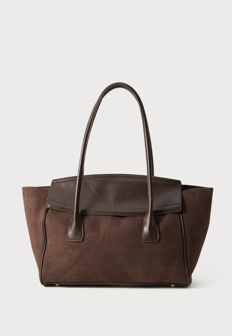 Sac fourre-tout en daim marron avec un design structuré, des accents en cuir lisse, des poignées allongées et une couture contrastante subtile.