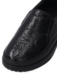 Black slip-on shoe with a textured, crackled leather upper and solid black rubber sole. Features a smooth design and elastic side panels.
