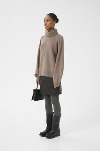 Suéter de cuello alto de punto grueso beige, falda mini de cuero negra, leggings grises, botas altas negras y bolso pequeño negro.