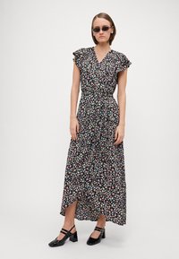 Robe maxi noire, ornée d'un imprimé floral avec des fleurs roses, bleues et blanches. Tissu léger, design à encolure en V et manches volantées.