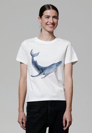 T-shirt en coton blanc avec un graphisme de baleine bleue dans différentes teintes de bleu. Manches courtes et col rond.