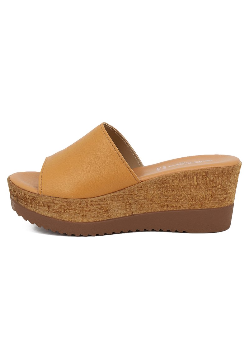 Sandalo con zeppa in pelle marrone chiaro, base in sughero, con punta aperta e superficie liscia. Presenta una fascia superiore ampia e una suola scanalata per una maggiore aderenza.