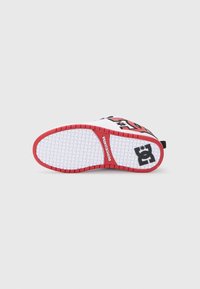 Potplat tenisice s bijelim gaznim slojem, crvenim detaljima, brendingom DC Shoe USA u središtu i crnim DC logotipom blizu pete.