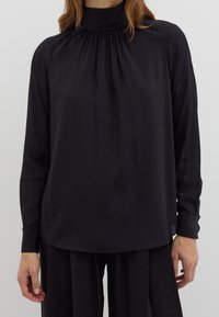 Black long-sleeve blouse with a high collar, featuring gathered fabric at the neck and fitted cuffs. Smooth, lightweight material.