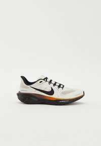 Nike running shoe featuring a white mesh upper, black accents, orange and black speckled midsole, and a rounded toe with lacing system.