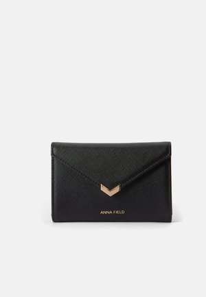 Black textured wallet with a triangular flap closure, featuring a gold accent and the brand name "ANNA FIELD" embossed at the bottom.