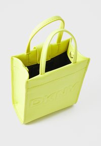 Sac fourre-tout en cuir jaune néon avec logo "DKNY" embossé, doté de deux poignées courtes et d'une forme rectangulaire structurée. Texture lisse, ouverture supérieure sans fermeture.