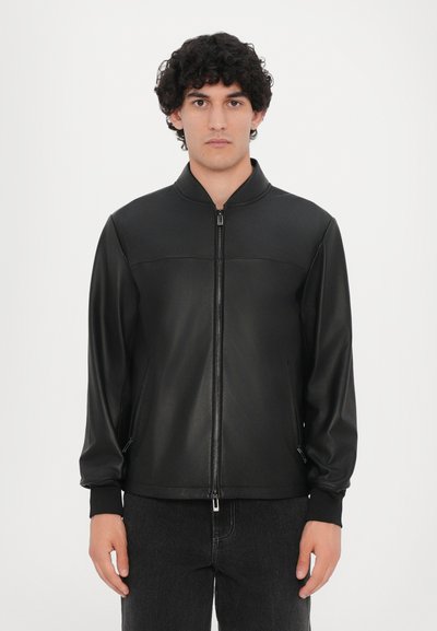 Veste bomber noire en matériau lisse, dotée d'une fermeture éclair sur le devant, d'un col montant et de poignets côtelés. Pas de motifs ni de logos visibles.