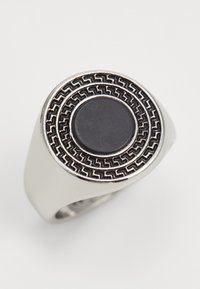 Anillo de plata con una gema negra circular en el centro, rodeado por una banda con patrón que presenta un diseño geométrico y un acabado pulido.