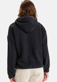 Sweat à capuche gris foncé en polaire avec une surface texturée, doté d'une capuche et de manches longues. Couture visible au bas et sur le côté.