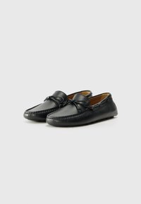 Schwarze Lederloafers mit runder Spitze, dekorativem Schleifenmotiv und gesteppten Details. Weiche Textur mit bequemem Schlupfdesign.