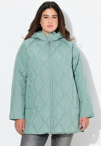 Ljusgrön vadderad pufferjacka med zip-fram, huva och sidofickor. Tyget har en jämn struktur med diamantformade mönster.