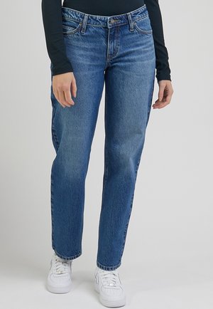 Lyseblå denimjeans med lige ben-design, som har fem lommer og en frontlynlås. Båret med en mørk langærmet top og hvide sneakers.