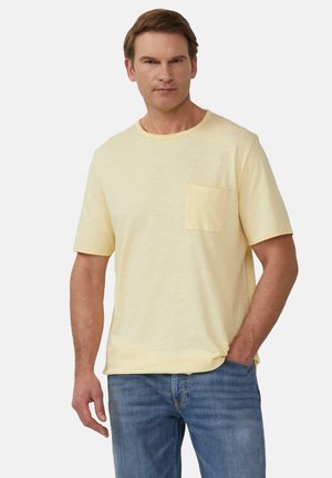 Korte mouwen pastelgele t-shirt met een ronde hals en een borstzak, gemaakt van een zachte, gestructureerde stof. Gedragen met blauwe denim jeans.