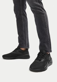 Pantofi sport negri, cu un superior din plasă texturată, vârf rotunjit și talpă ușoară. Șireturile și brandingul sunt, de asemenea, negre.