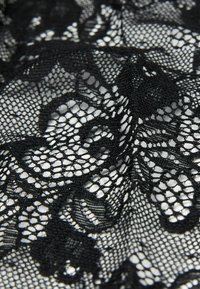 Tessuto di pizzo nero con intricati motivi floreali e una texture delicata e aperta. Il design enfatizza il contrasto e l'eleganza.