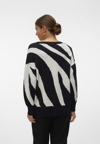 Maglione a righe bianche e nere con vestibilità ampia, texture a maglia, spalle basse e scollo ampio, caratterizzato da un audace motivo zebra.