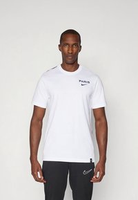 Biele bavlnené tričko s potlačou „PARIS“ v námorníckej modrej, logom Nike na hrudi a červeným detailom na pleci. Krátke rukávy a okrúhly výstrih.