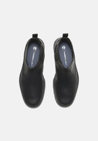 Zapatos negros tipo slip-on hechos de cuero suave, con puntera redonda, acentos laterales elásticos y una plantilla acolchada.